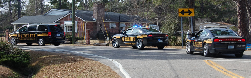 Two sheriff’s patrol cars and one SUV driving down a street